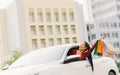 Happy Asian tourist woman raise shopping bags on modern white car, look up at copy space. Shopaholic consumerism activity Royalty Free Stock Photo