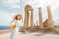 Asian Traveler with backpack walking in historical and archaeological site in Lindos Acropolis. Tourist attraction and