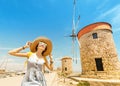 Asian traveler girl posing near famous Rhodes attraction - old windmills. Vacation in Greece concept Royalty Free Stock Photo