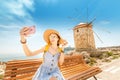 Asian traveler girl taking selfie near famous Rhodes attraction - old windmills. Vacation in Greece concept Royalty Free Stock Photo