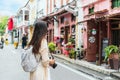 Happy Asian traveler woman take a photo while walking on the city street. Travelling in Phuket Old Town in Thailand concept Royalty Free Stock Photo