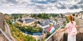 happy Asian traveller girl holds the flag of Luxembourg and admires the great panoramic view of the Grund town from the viewing