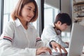 Happy asian university students sitting and working together on laptop in library, preparing for exams Royalty Free Stock Photo