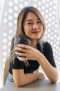 Happy woman in black t-shirt sipping hot coffee in white coffee shop. Royalty Free Stock Photo