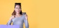 Happy Asian woman carry shopping bags and pointing at credit card smiling over yellow background, empty space Royalty Free Stock Photo