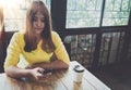Happy Asian woman chatting on her mobile phone while relaxing in cafe during free time, Royalty Free Stock Photo