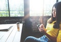 Happy Asian woman chatting on her mobile phone while relaxing in cafe during free time Royalty Free Stock Photo