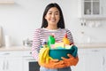 Happy asian woman with cleaning tools standing at kitchen