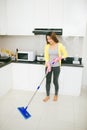 Happy asian woman cleans floor in the kitchen