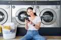 Happy Asian woman doing laundry. She was listening to her favorite song while waiting for her clothes in a laundry shop Royalty Free Stock Photo
