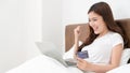 Happy asian woman doing online shopping at home, Women shopping online with credit card and laptop on the bed at home Royalty Free Stock Photo