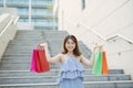 Happy Asian woman going down stairs with many colorful shopping bags. Lifestyle and shopping concept Royalty Free Stock Photo
