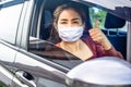 Happy Asian woman hand thump up and smiling in a car wearing protective mask before driving , covid-19 pandemic, new normal Royalty Free Stock Photo