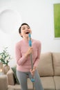 Happy asian woman in headphones with mop and bucket cleaning floor and singing at home Royalty Free Stock Photo