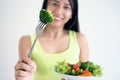 A happy Asian woman with a healthy salad dish, holding fork with a large broccoli. Food for good shape Royalty Free Stock Photo