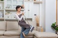 Happy asian woman holding with mop cleaning floor and singing at home. Housekeeping concept Royalty Free Stock Photo