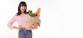 Happy Asian woman holding paper bag full of fresh vegetable groceries isolated on white copy space background Royalty Free Stock Photo