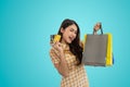 Happy Asian woman holding shopping bags and showing credit card isolated on blue background Royalty Free Stock Photo