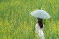 Happy asian woman lifestyle hand holding umbrella in the meadow yellow flower sunrise. Active Outdoor Relax and enjoy in Nature.