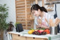 Happy asian woman looking recipe tablet kitchen reading cooking at home,University colleague student study online with social Royalty Free Stock Photo