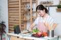 Happy asian woman looking recipe tablet kitchen reading cooking at home,University colleague student study online with social Royalty Free Stock Photo