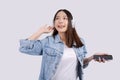 Happy Asian woman looks out while listening to music with headphones and holding her mobile phone, a blank screen, white Royalty Free Stock Photo