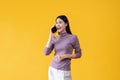 A happy Asian woman is making a call to someone, talking on the phone. an isolated yellow background Royalty Free Stock Photo