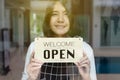 Happy asian woman owner turning open sign after lockdown quarantine in modern cafe Royalty Free Stock Photo