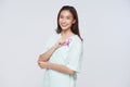 Happy asian woman patient showing pink badge ribbon chest to support breast cancer cause. breast cancer awareness concept Royalty Free Stock Photo