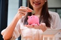 Happy woman putting coin into piggy bank. Business investment finance accounting concept. Royalty Free Stock Photo