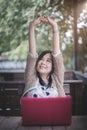 Happy asian woman raise arm up from body and muscles while working with laptop computer at her desk home office, smiling mature Royalty Free Stock Photo