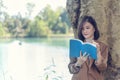 Happy asian woman reading book outdoor in green park nature. Reading book magazine relaxation woman. Leisure portrait woman smile