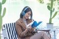 Happy asian woman reading book use headphones listen to music outdoor in green park nature. Reading book magazine, Music therapist Royalty Free Stock Photo