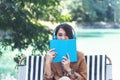 Happy asian woman reading book use headphones listen to music outdoor in green park nature. Reading book magazine, Music therapist Royalty Free Stock Photo