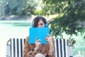 Happy asian woman reading book use headphones listen to music outdoor in green park nature. Reading book magazine, Music therapist Royalty Free Stock Photo