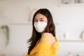 Happy Asian Woman received anti virus vaccine cheerful thumbs up with yellow bandage. young female wearing medical face mask enjoy