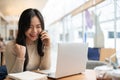 A happy Asian woman rejoicing after receiving good news over the phone while working remotely Royalty Free Stock Photo