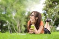 Happy Asian woman resting and looking beside in park with smartphone. People and lifestyles concept. Technology and Beauty theme. Royalty Free Stock Photo