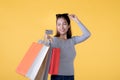 Happy Asian woman with shopping bags and credit card smiling over yellow background, empty space Royalty Free Stock Photo