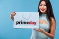 Happy asian woman at shopping holding bag and phone isolated on blue background on black friday and primeday holiday