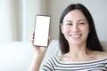 Happy asian woman showing blank phone screen at home