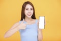 Happy asian woman showing mobile phone blank screen on yellow background Royalty Free Stock Photo