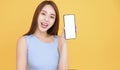 Happy asian woman showing mobile phone blank screen on yellow background Royalty Free Stock Photo