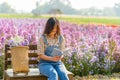 Happy asian woman sitting on bench and reading a book in the park with flower garden Royalty Free Stock Photo