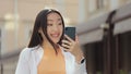 Happy asian woman speaking on video call in street. Smiling woman making video call on mobile phone in city walk. Girl Royalty Free Stock Photo