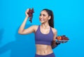 Happy asian woman in sportswear eating fresh fruit gain energy for workout on blue background. Sport, wellbeing and healthy food Royalty Free Stock Photo