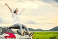 Happy Asian woman spread arms widely and breathed fresh air with happiness mood in evening after sunset on car roof. People