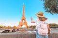 Asian woman student with backpack observing view of the Eiffel Tower in Paris. Travel and education in France concept