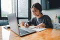 Happy asian woman student watching lesson online and studying from home. Young woman taking notes while looking at