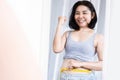 happy Asian woman success on dieting and weight loss measuring her waist smiling in front of a mirror Royalty Free Stock Photo